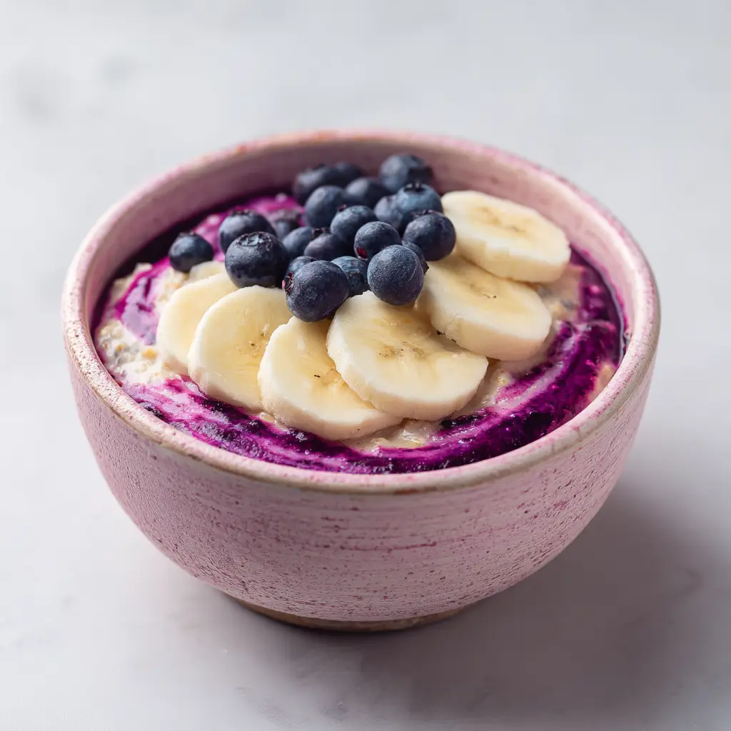 A spoonful of easy no-cook oatmeal with blueberries and banana being lifted from a bowl, showcasing the delicious, thick consistency.