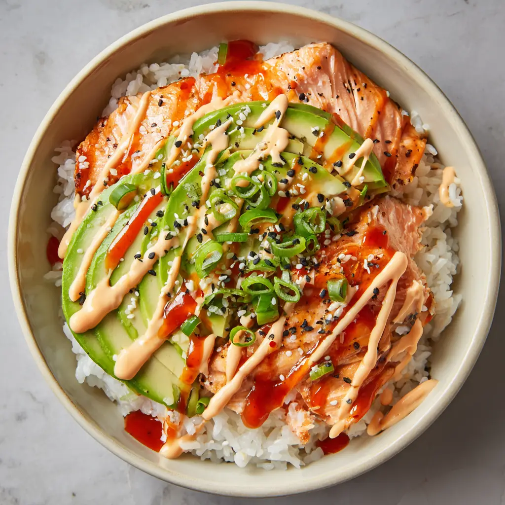 Lightly seared and flaked salmon fillet resting on a cutting board next to smoothly sliced and fanned fresh green avocado.