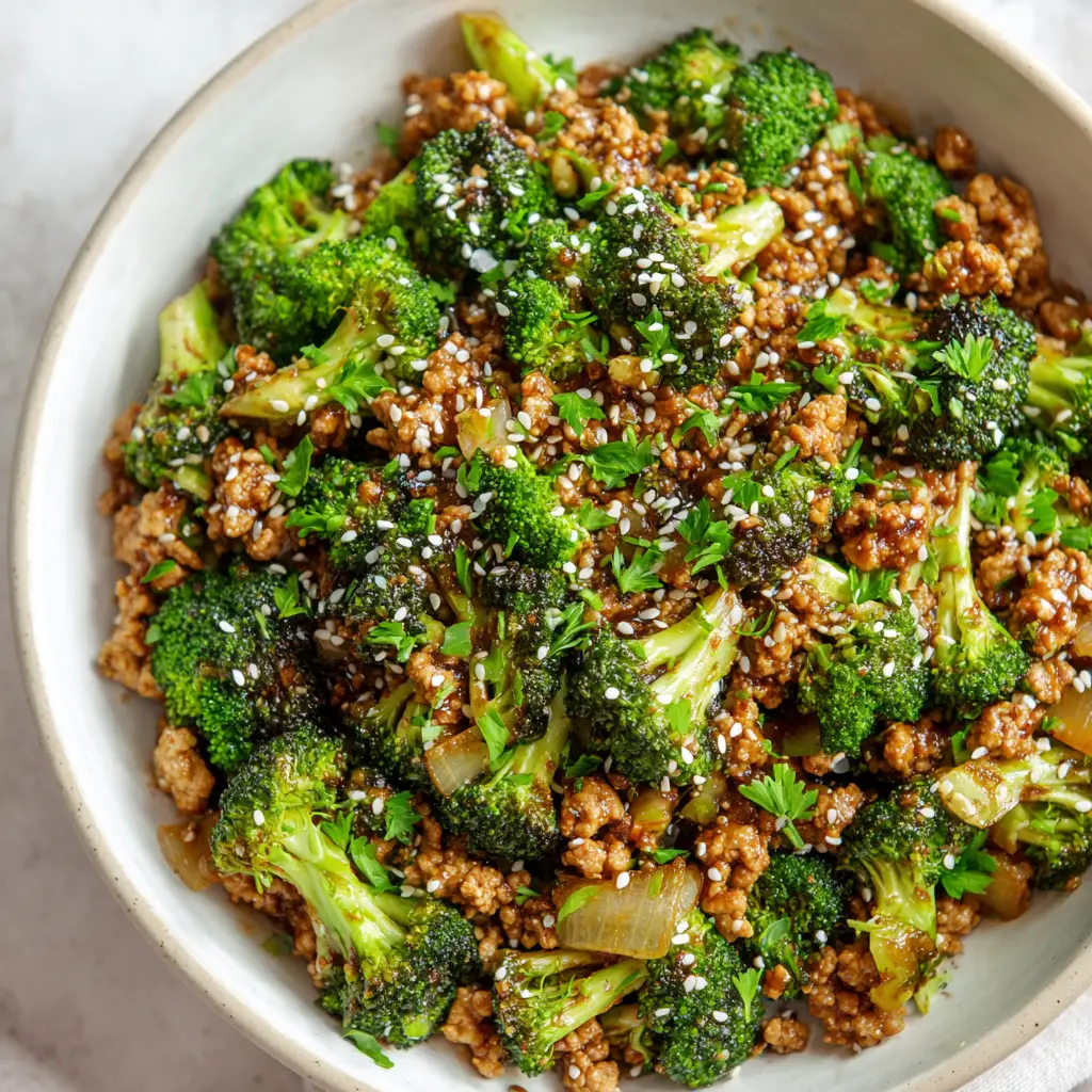 Unedited, handheld smartphone photo style image of a savory ground turkey and broccoli stir-fry generously garnished with white sesame seeds and finely chopped fresh green parsley.