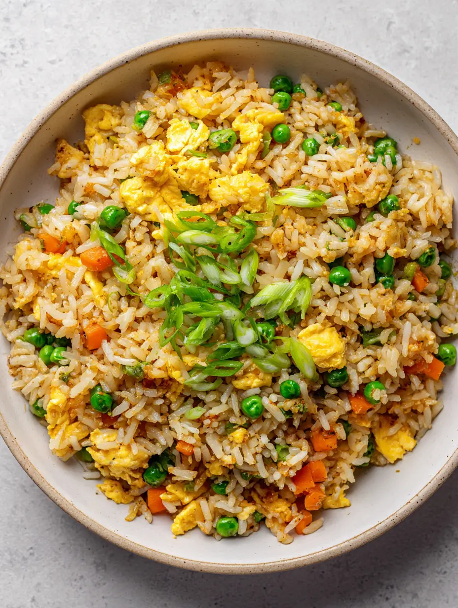 Close-up of Egg Fried Rice with soy-seasoned grains and fluffy egg clusters in a white bowl.