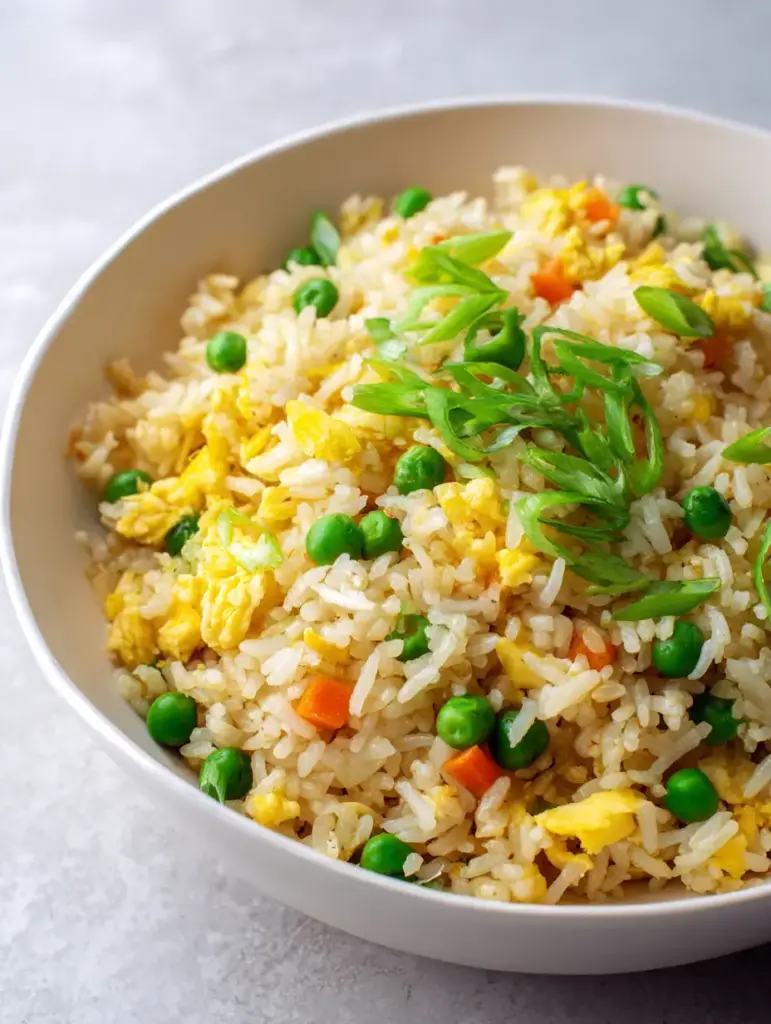 Soft daylight hitting a bowl of Egg Fried Rice, highlighting the glistening oil sheen and fresh scallions.