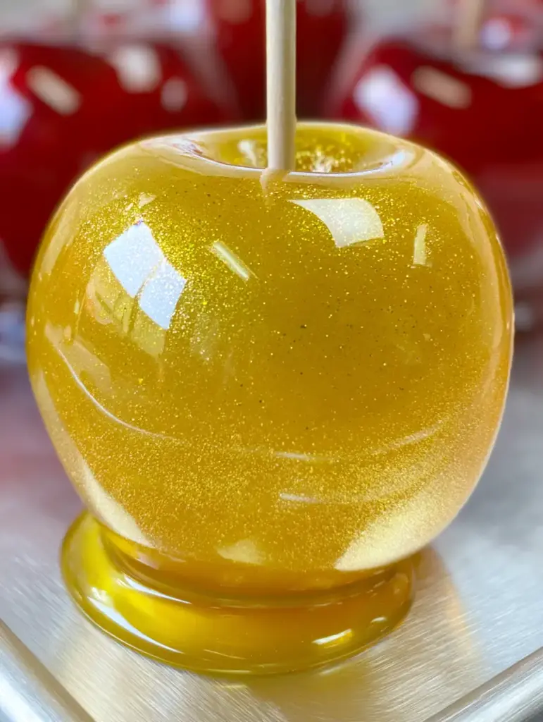 A handheld smartphone photo showing the reflective yellow glaze of the Pineapple Lemonade Candy Apples.