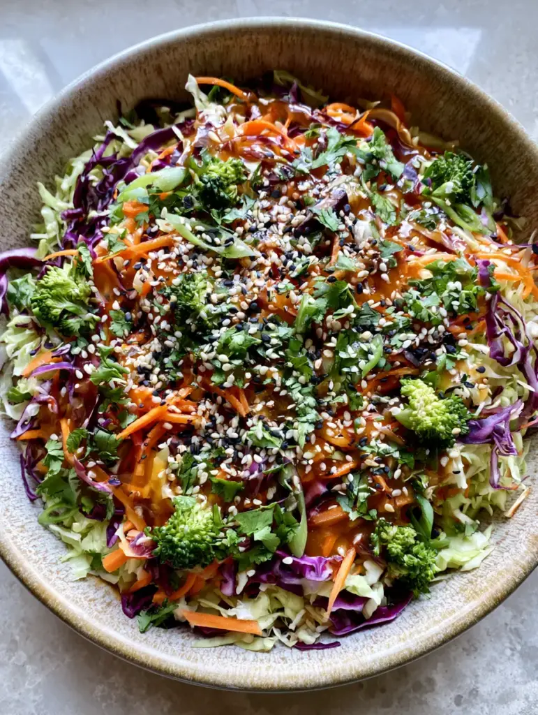 Close up photo of Crunchy Asian Cabbage Salad showing vibrant ribbons of purple cabbage and matchstick carrots in a translucent dressing. (Crunchy Asian Cabbage Salad)
