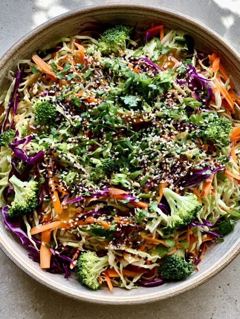 Top down view of a ceramic bowl with Crunchy Asian Cabbage Salad garnished with black and white sesame seeds and scallions.