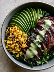 Close-up of a seared steak and avocado bowl with cilantro cream drizzle. (Whole30 Steak Bowl)