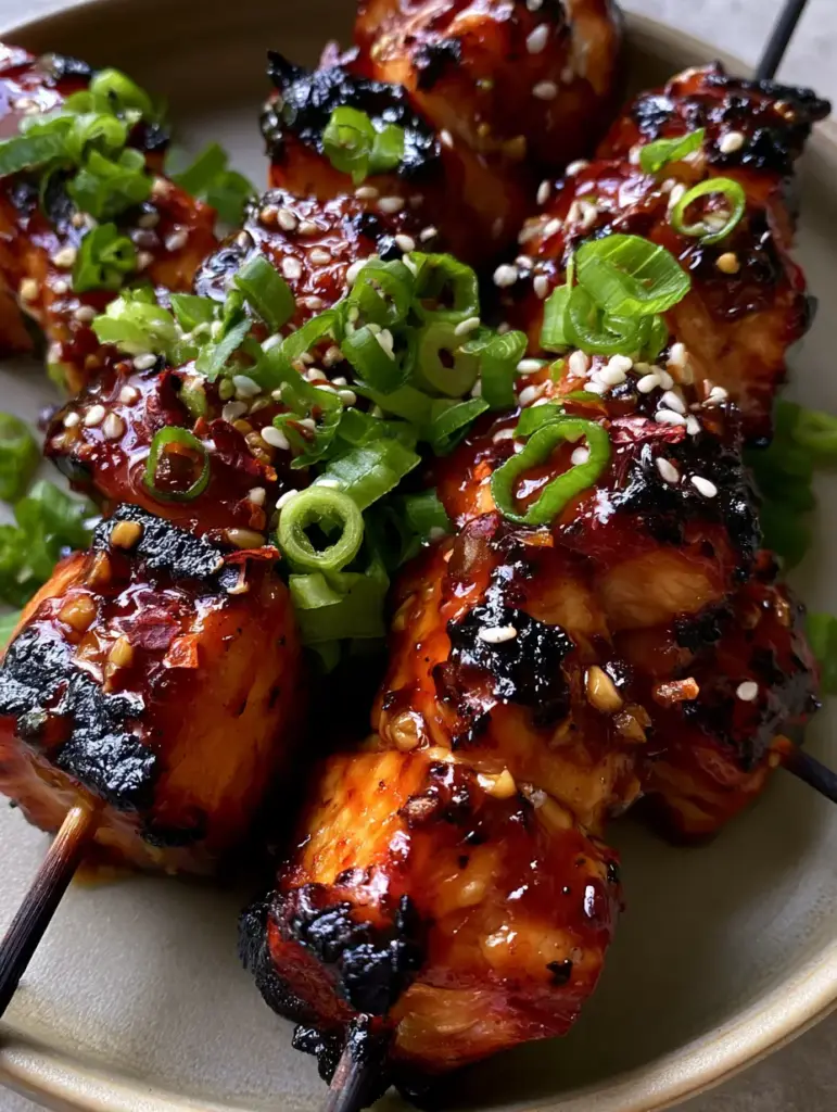 Top-down view of charred honey garlic chicken skewers showing thick glaze and minced garlic bits. (Honey Garlic Chicken Skewers)