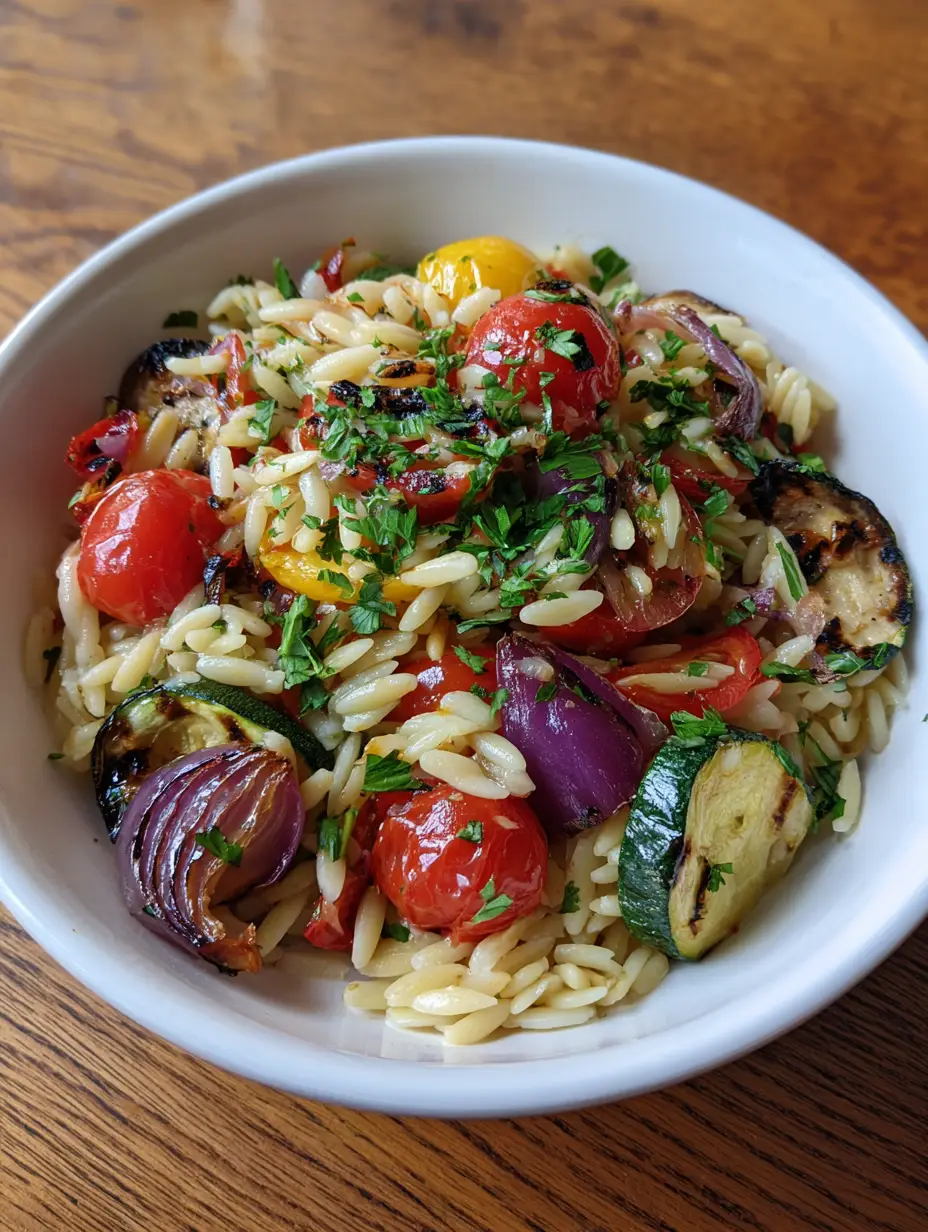 Close up of charred zucchini rounds and blistered cherry tomatoes in a white bowl with orzo pearls. (Roasted Vegetable Orzo Salad)