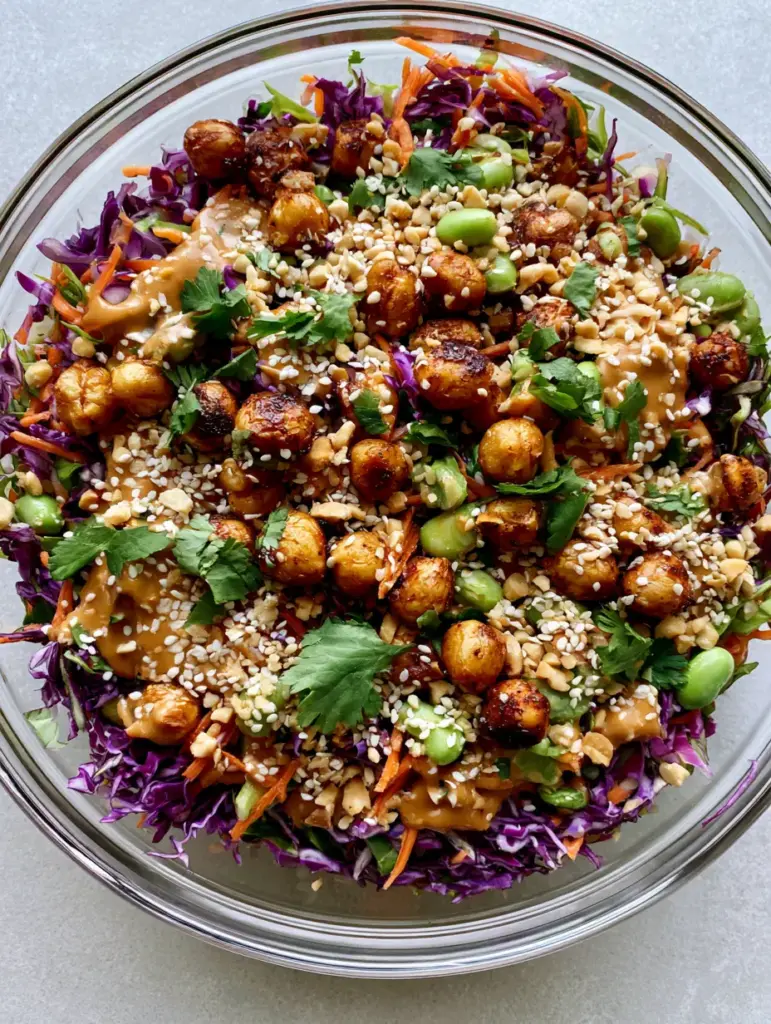 Close up of thick peanut sauce drizzled over shredded cabbage and sesame seeds in a Thai Chickpea Salad.