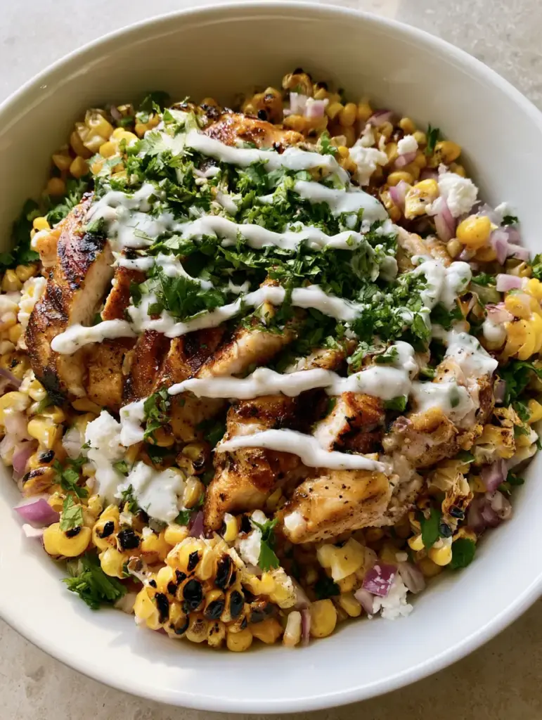 Overhead view of Chicken Street Corn Salad with a creamy lime dressing drizzle and fresh cilantro.