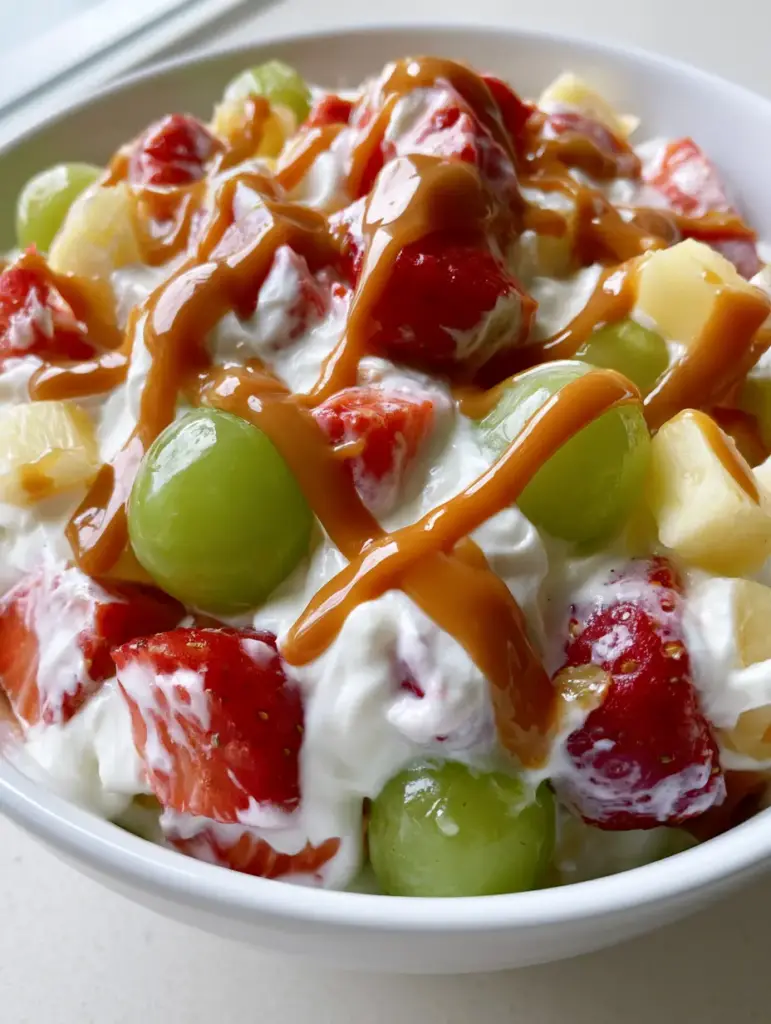 Detailed view of Cheesecake Fruit Salad showing the moist textures of the fruit and the glossy sheen of the caramel drizzle.
