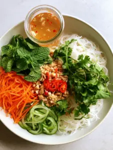 Overhead view of a vibrant Vietnamese Noodle Salad showing soft vermicelli topped with sections of fresh carrots and cucumbers.